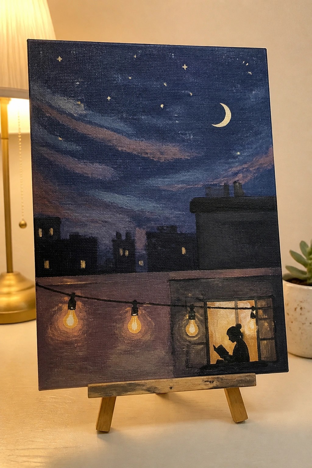 Starry night painting with crescent moon, glowing string lights, and silhouetted reader in window