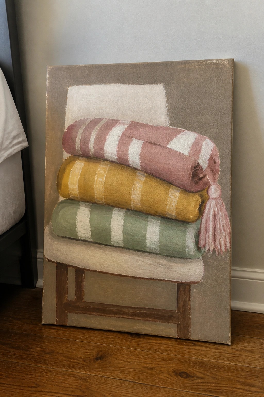 Painting of pink, yellow, and green striped rolled towels stacked on a stool with tassel.