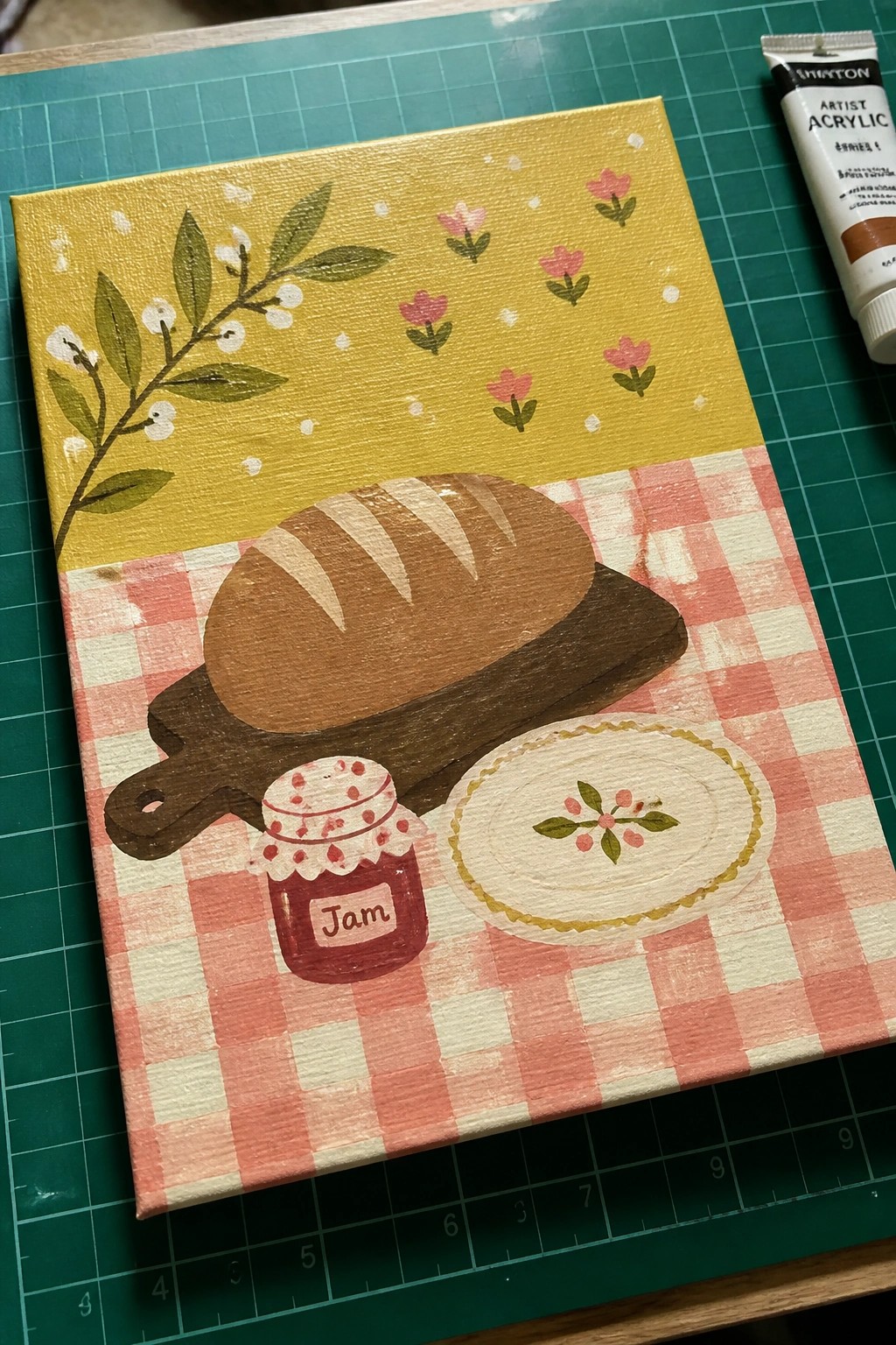 Folk art painting of bread, jam jar, and plate on red checkered cloth with yellow florals