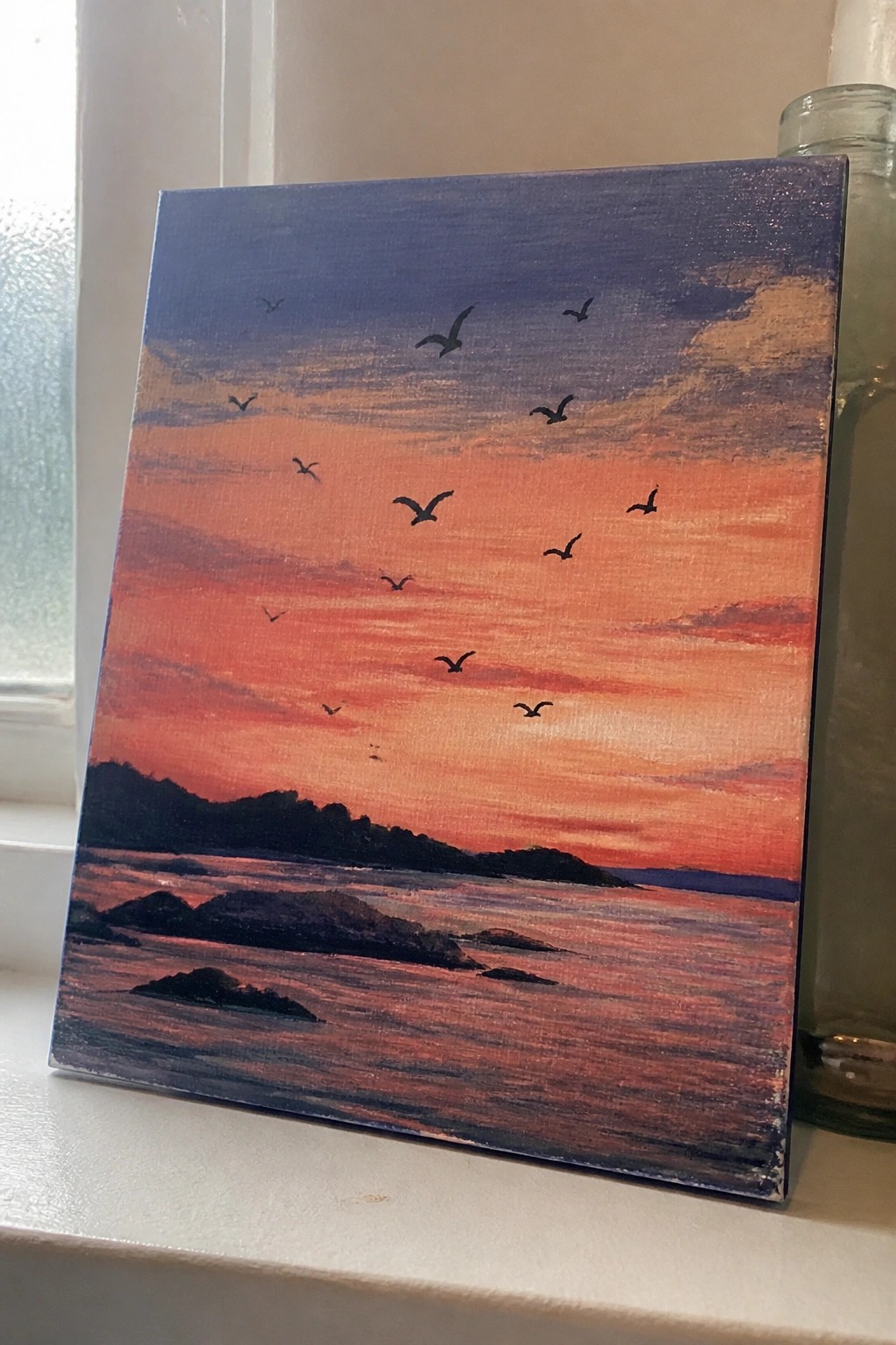 Canvas painting of vibrant orange sunset over sea with silhouetted islands and flying birds