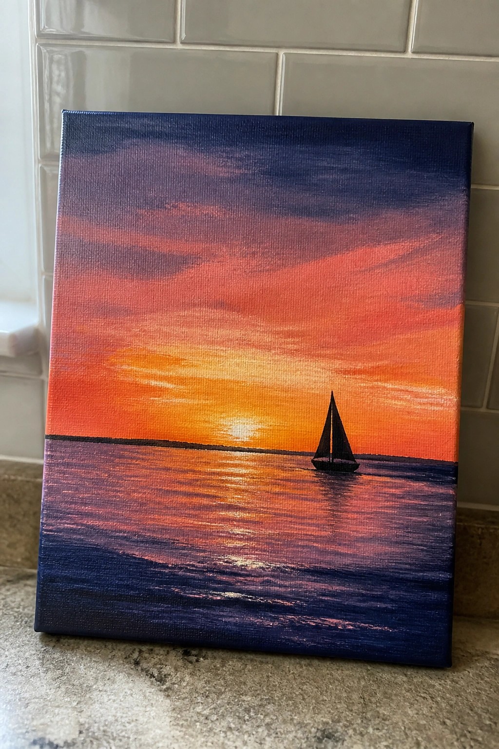 Vibrant sunset painting on canvas with orange sky, reflective sea, and sailboat silhouette