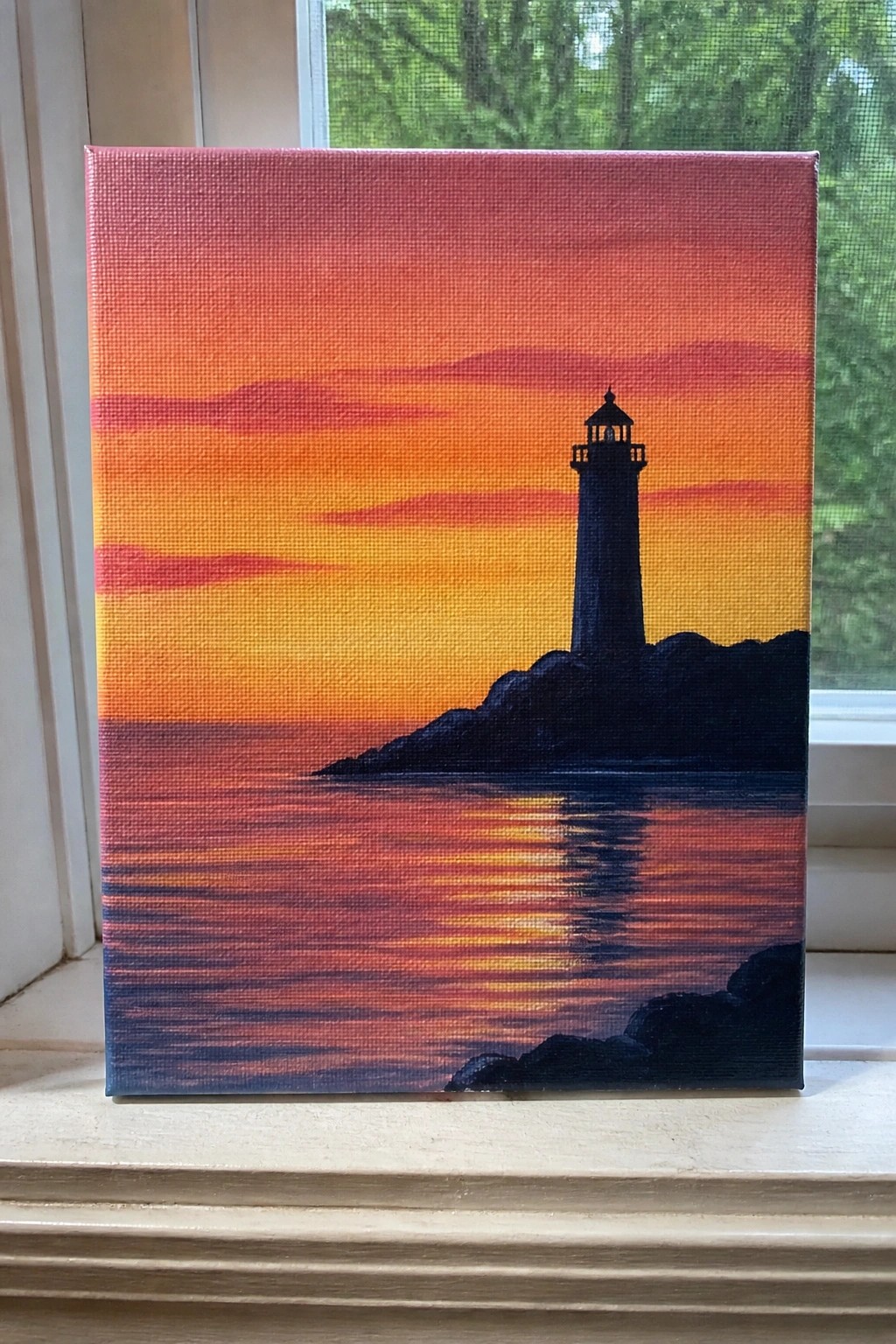Vibrant sunset canvas with silhouetted lighthouse on rocks reflected in orange striped waters