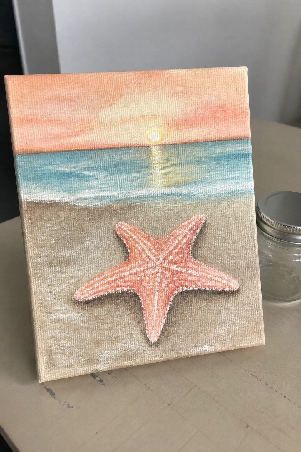 Acrylic painting of sunset over ocean with orange starfish on sand
