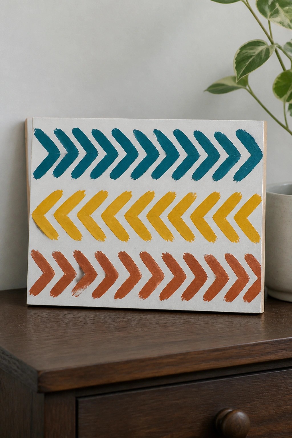 Canvas with teal, yellow, and orange chevron rows on dark wooden surface