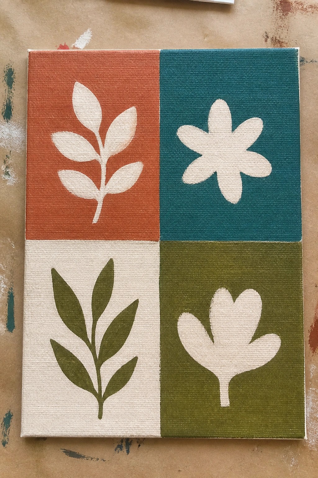 Four-section canvas with orange, teal, cream, and olive quadrants showing leaf and flower designs.