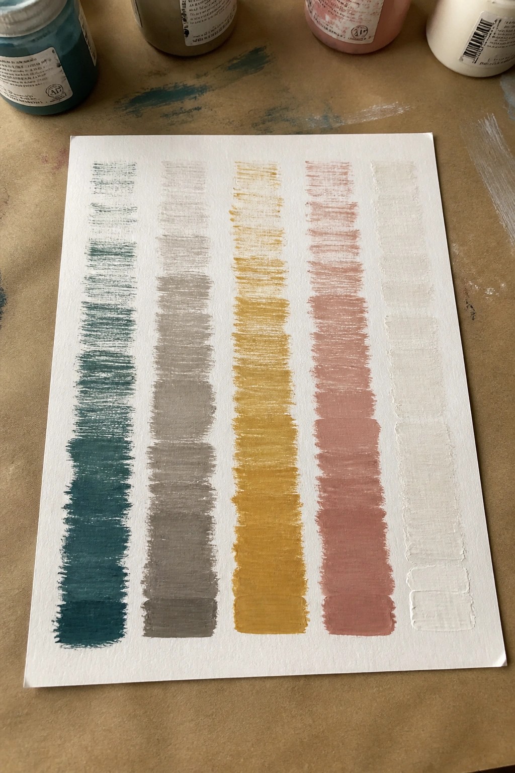 Vertical paint swatches in teal, gray, yellow, rose, and white on paper