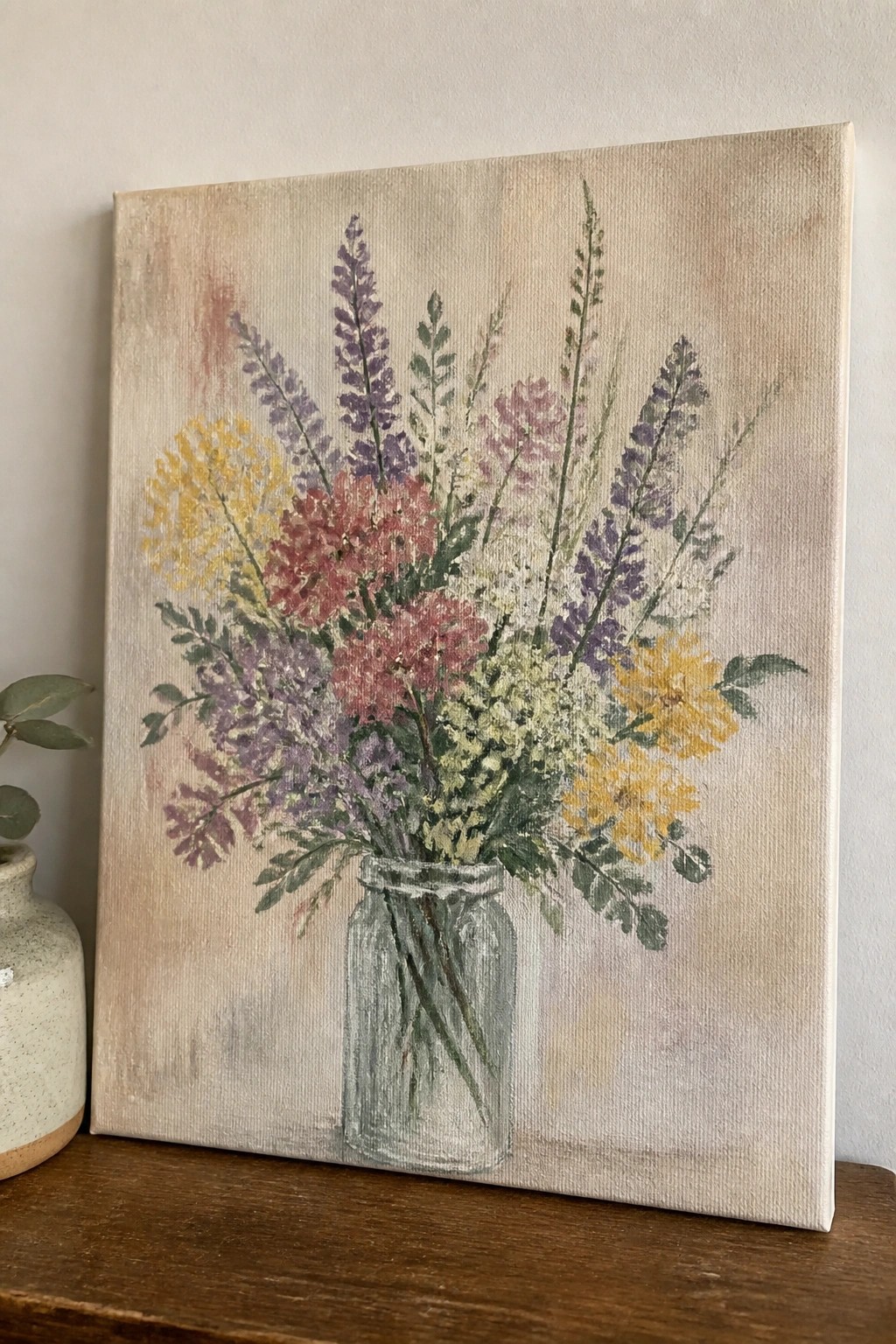 Colorful wildflowers in a glass jar, painted on canvas with soft pastel background