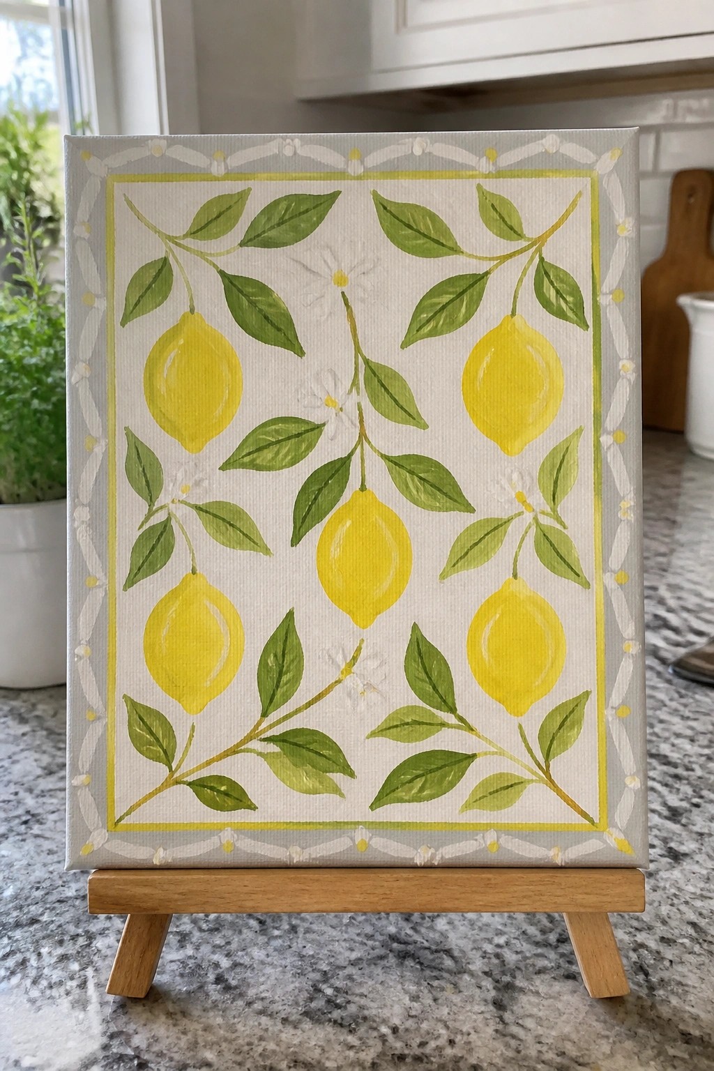 Canvas painting of yellow lemons and green leaves with decorative border on easel