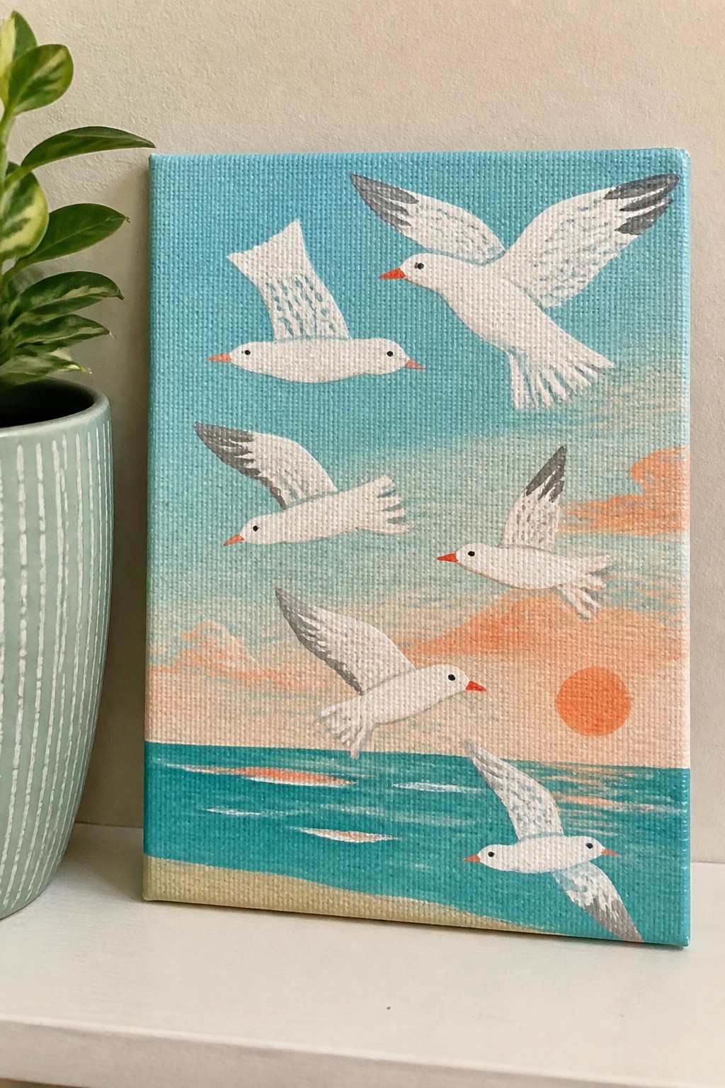 Painting of six white seagulls flying over turquoise ocean at orange sunset