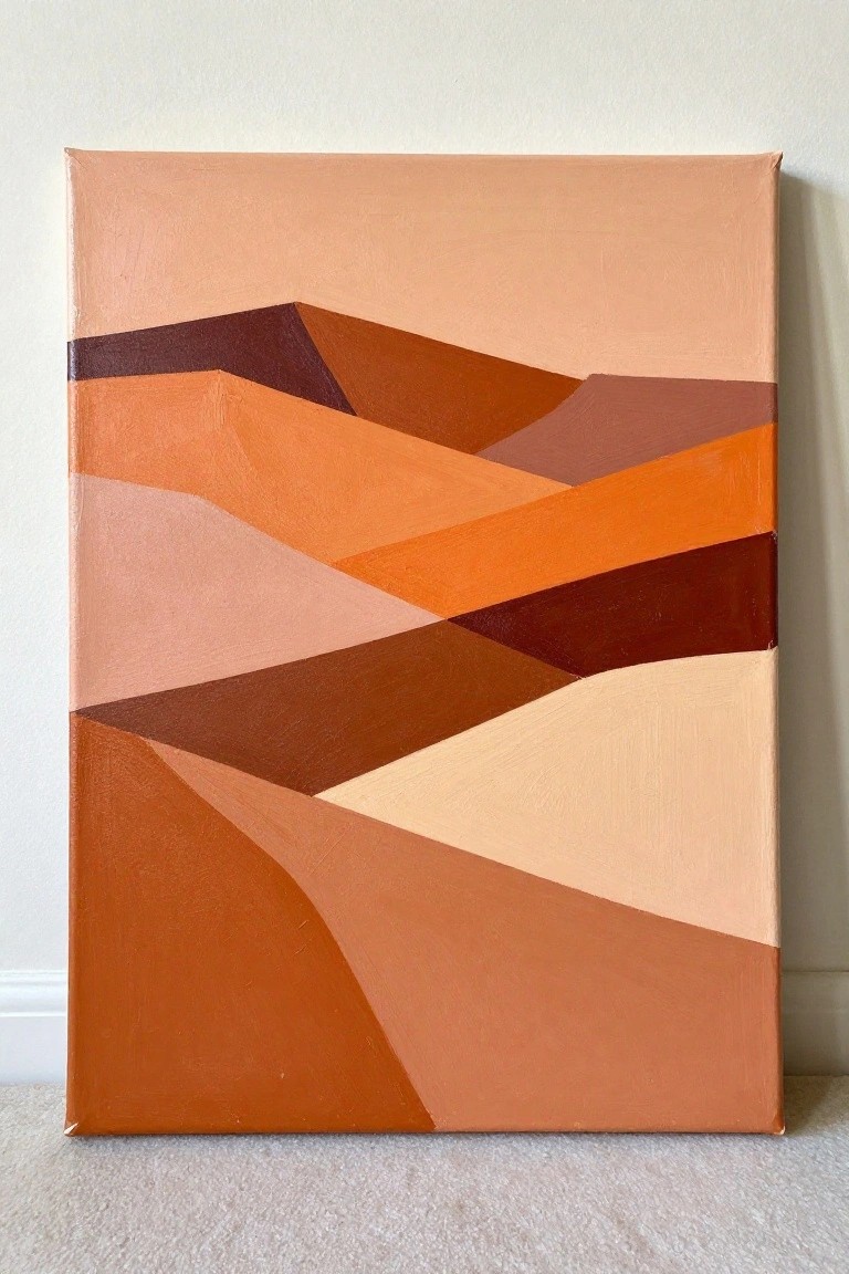 Abstract canvas with angular shapes in warm orange, brown, and peach tones on floor.