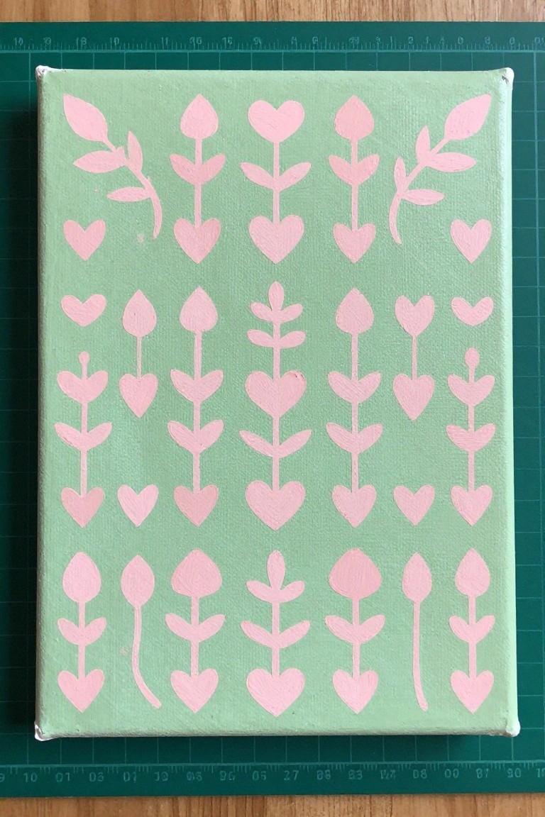 Light green canvas with pink heart, flower, and leaf patterns on cutting mat