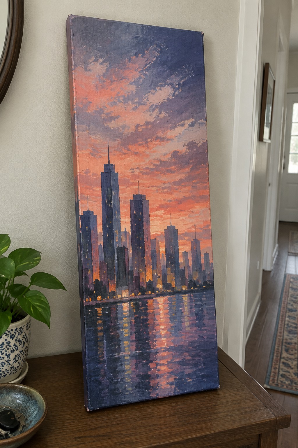 Impressionistic painting of skyscrapers at orange-purple sunset reflected in water on table