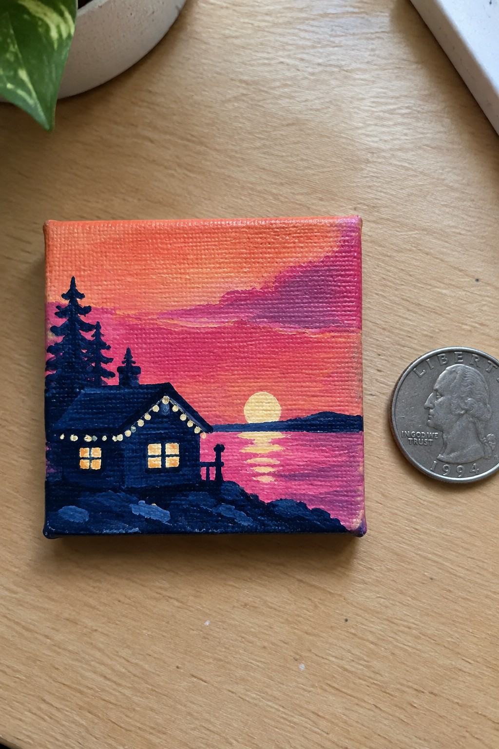 Miniature painting of glowing cabin at vibrant pink sunset by water beside quarter