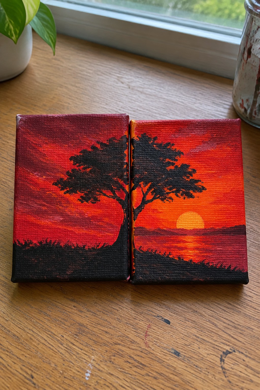 Two small canvases depicting a black tree silhouette against a red-orange sunset.