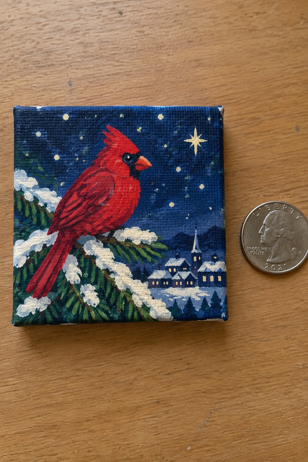Red cardinal on snowy pine branch in starry night painting beside quarter.