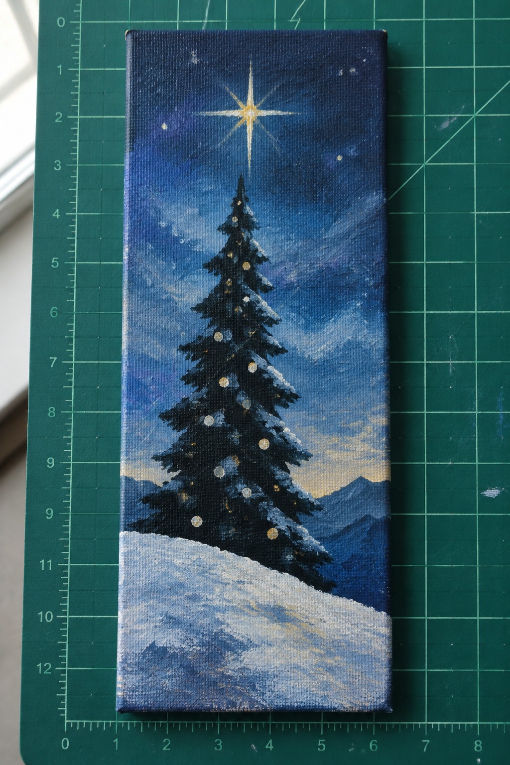 Canvas painting of snow-covered Christmas tree with lights beneath bright star in night sky.