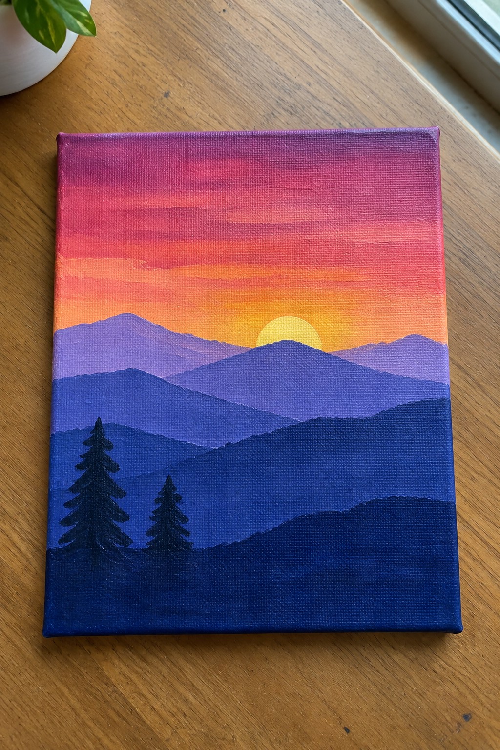 Layered mountain sunset painting with purple peaks, orange sky, yellow sun, and dark pine trees.