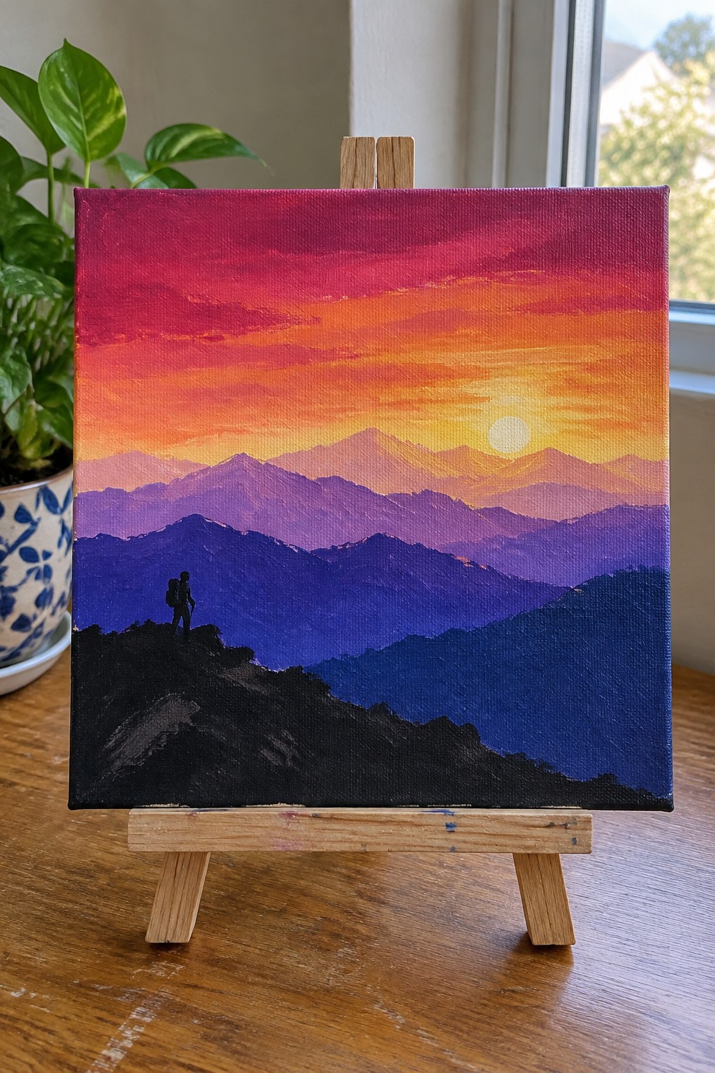 Acrylic painting of silhouetted hiker overlooking layered purple mountains under vibrant sunset sky