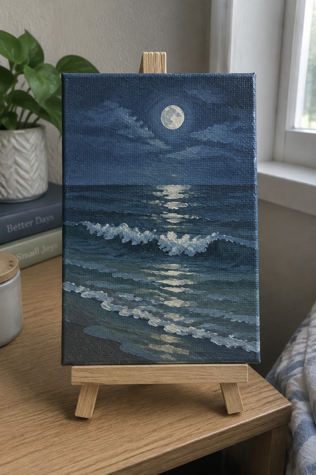 Small canvas on easel showing full moon over dark blue ocean waves