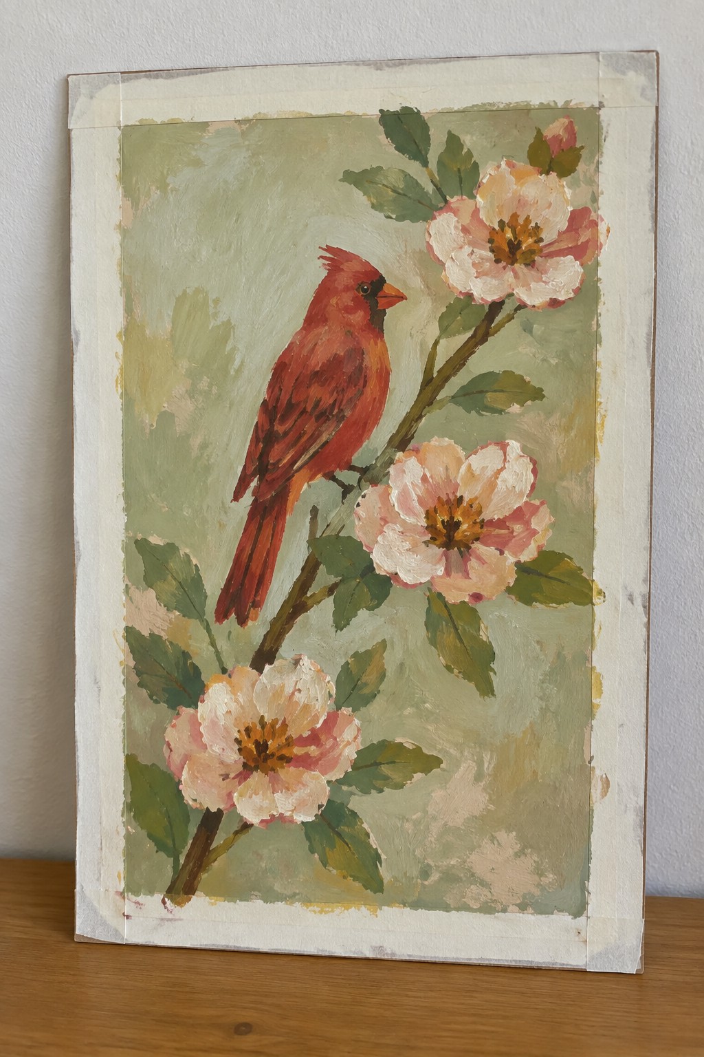 Red cardinal perched on branch amid pink-white flowers and green leaves in painting