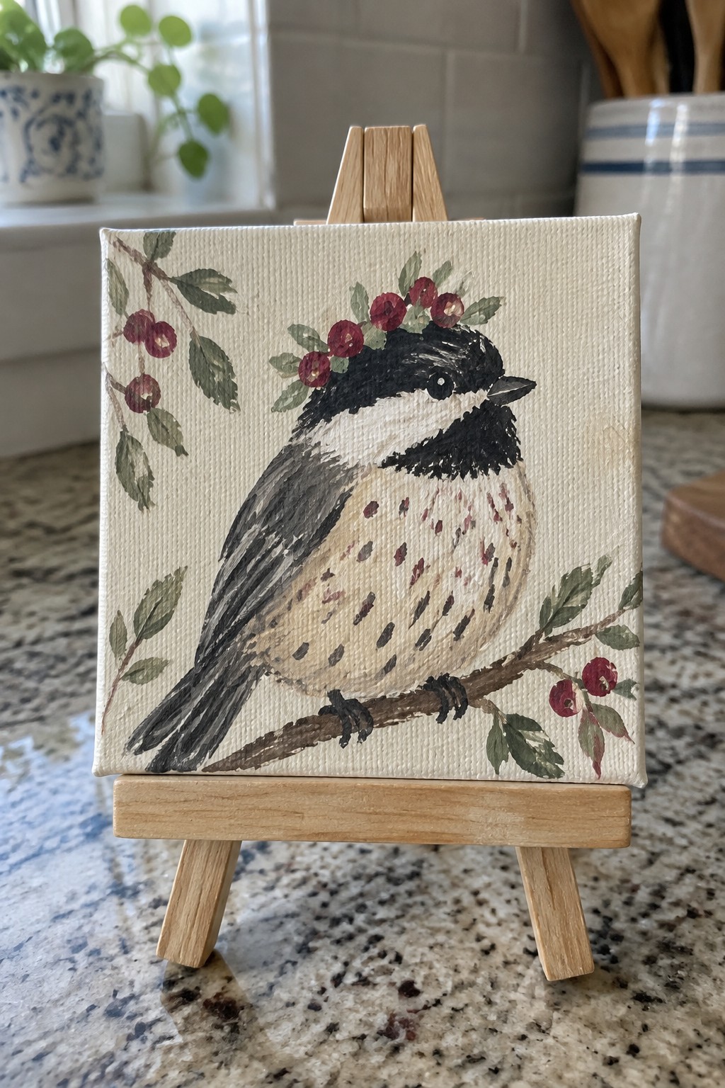 Small canvas painting of chickadee with red berry crown on wooden easel
