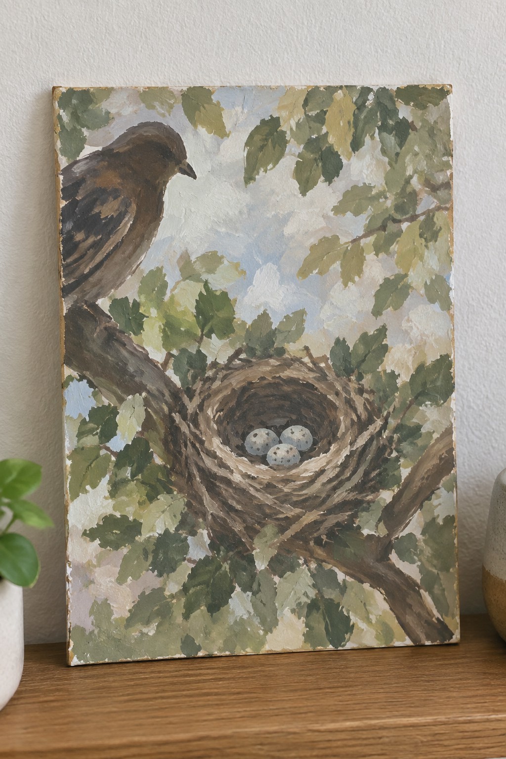Painting of brown bird beside nest with three speckled eggs amid green leaves