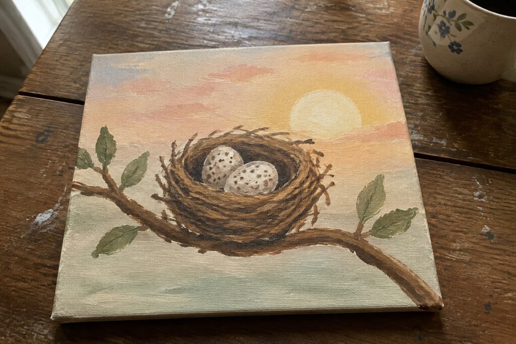 Painting of three speckled eggs in a nest on a branch against a sunset sky.