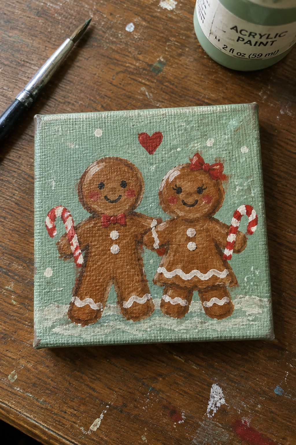 Gingerbread couple with bows holding candy canes under red heart on green canvas