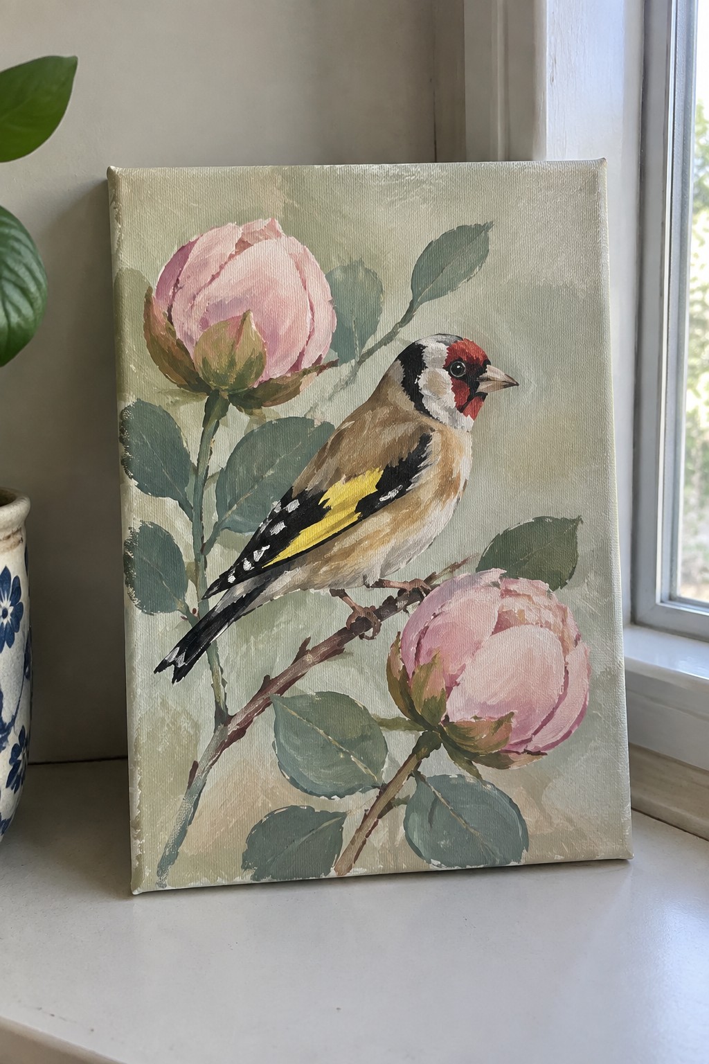 Canvas painting of goldfinch perched on branch with pink roses and green leaves