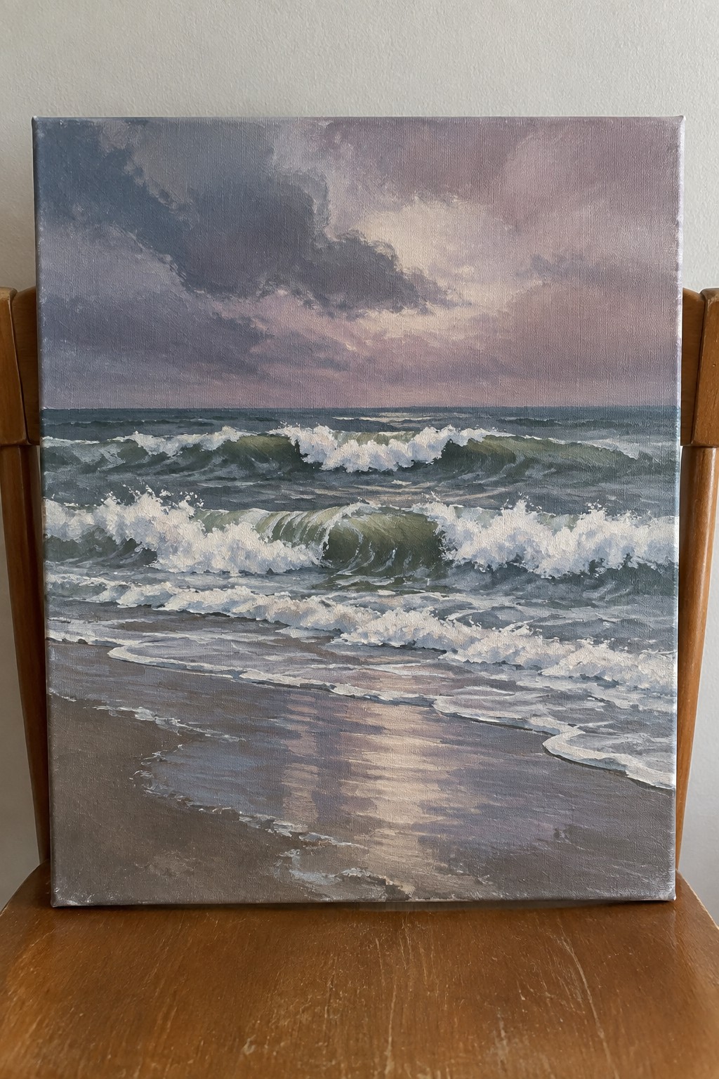 Seascape painting of crashing green waves under purple clouds on wooden chair