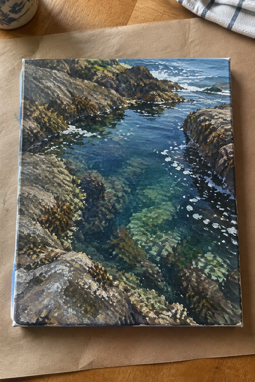 Square canvas painting of rocky cove with clear turquoise water, white foam and cliffs