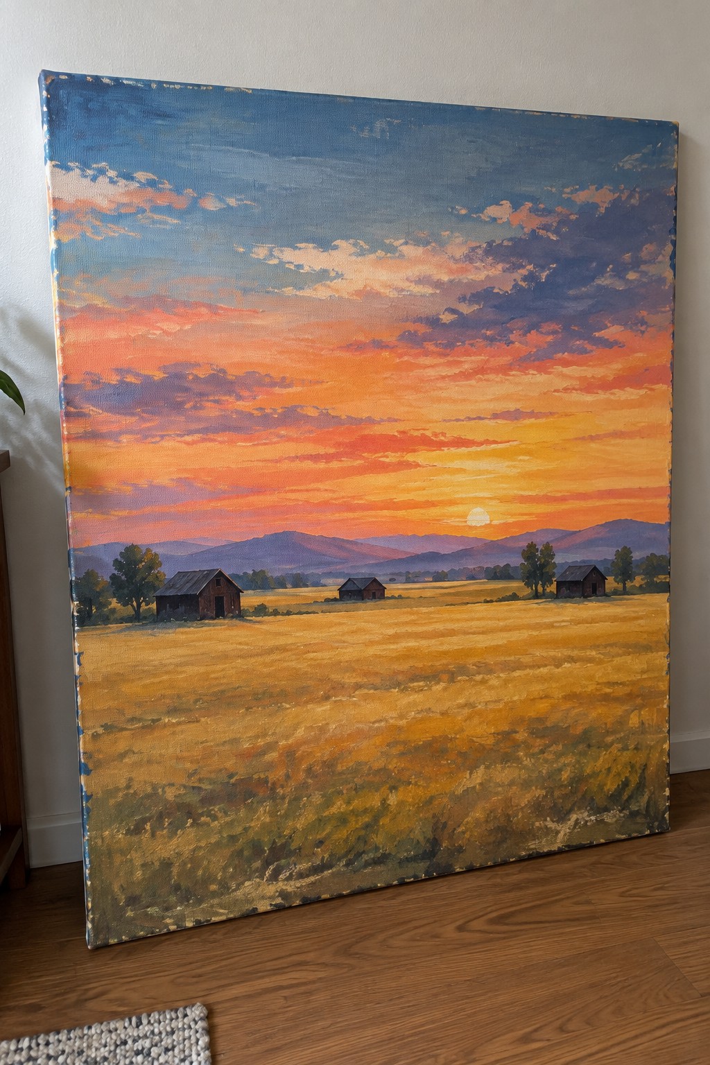 Vibrant landscape painting of golden field with barns at colorful mountain sunset