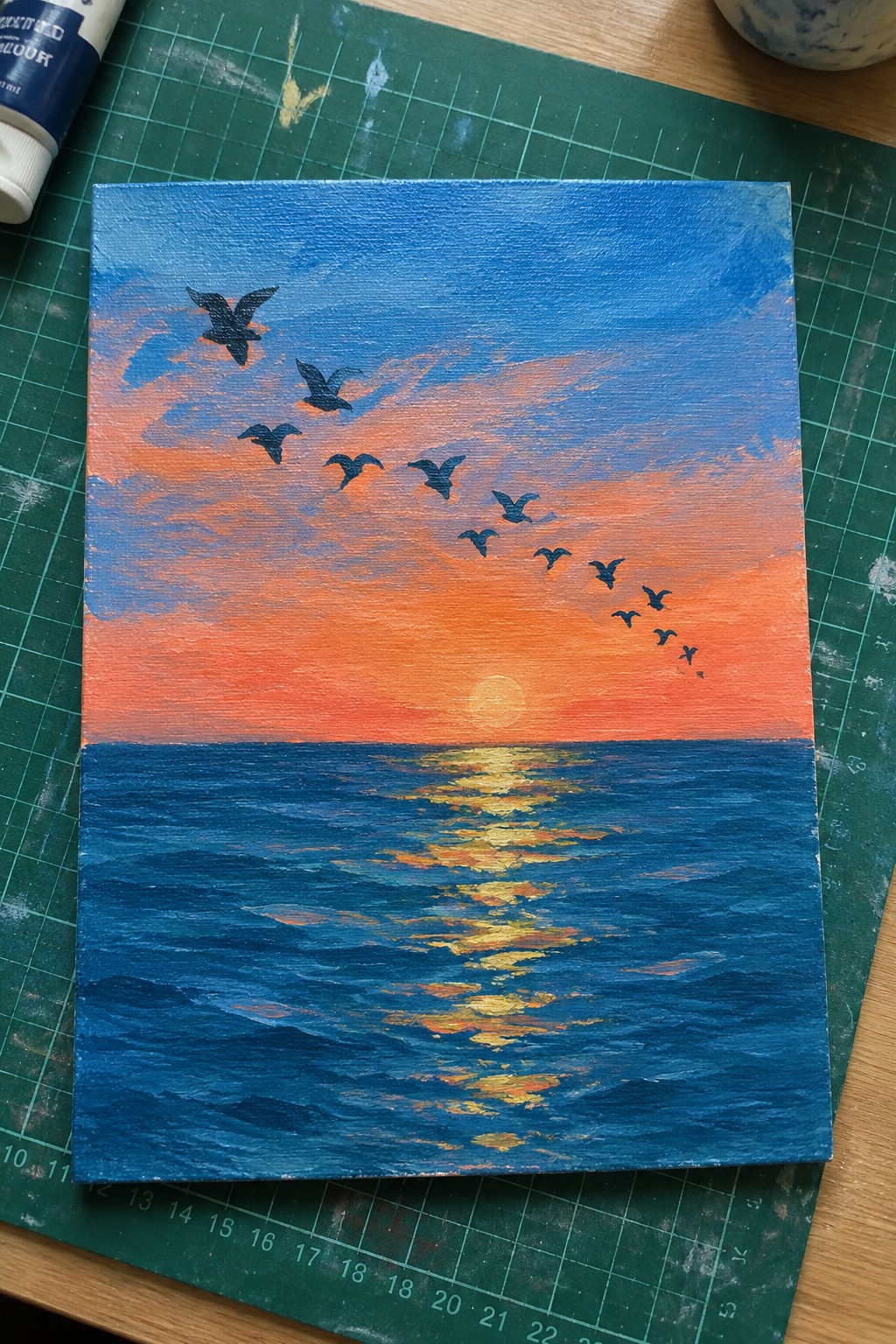 Sunset ocean painting with silhouetted birds and golden sun reflections on waves