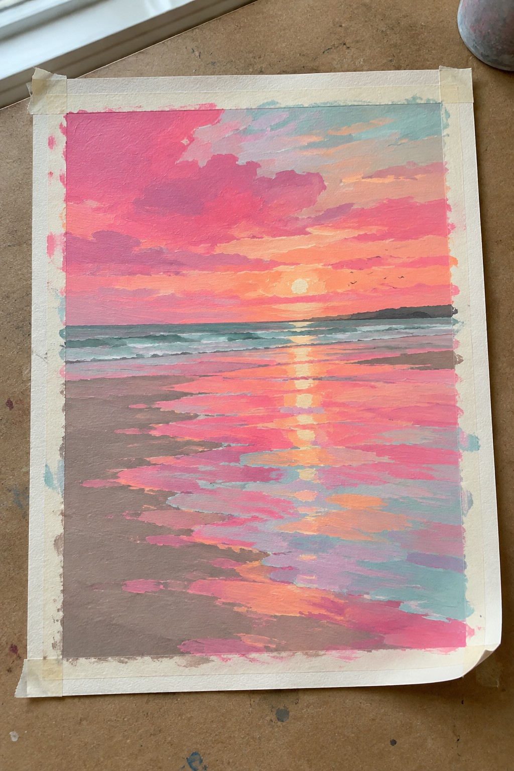 Vibrant pink-orange sunset painting over ocean with sun reflection on colorful wet sand