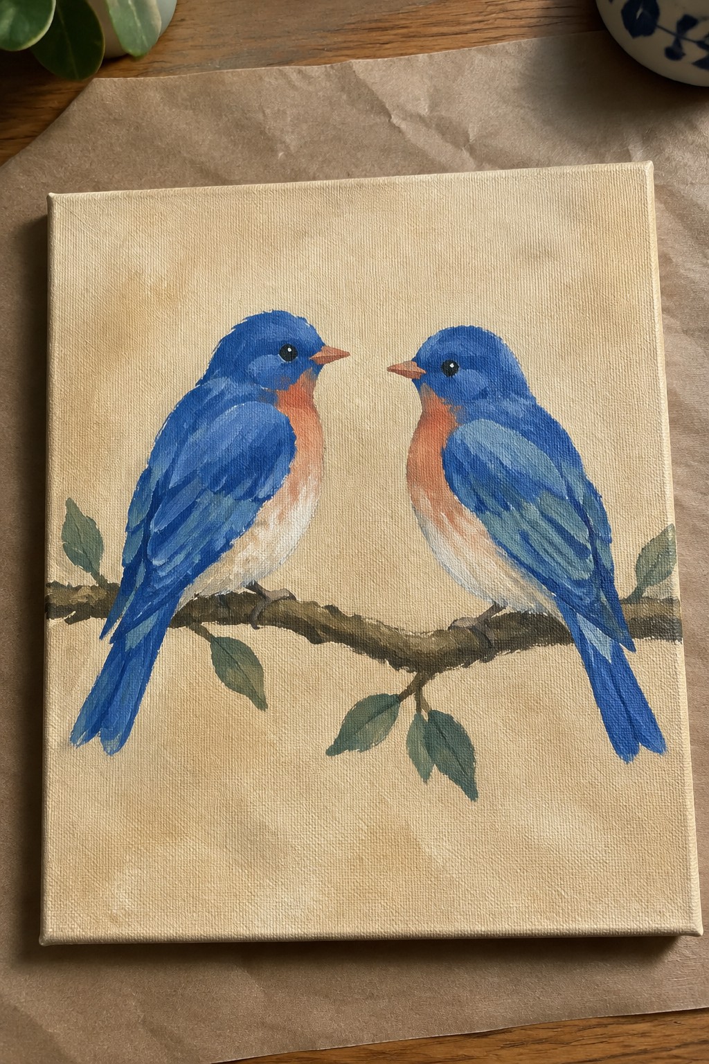 Two bluebirds with orange chests facing each other on a leafy branch