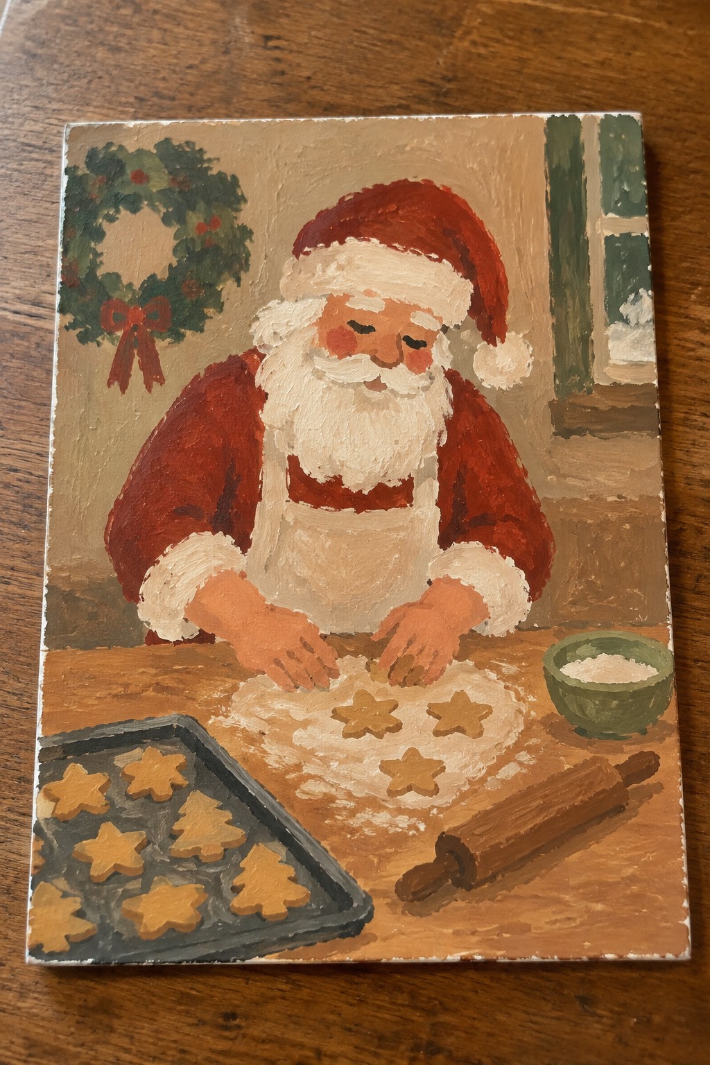 Santa in red suit and apron shapes star cookies beside tray and rolling pin