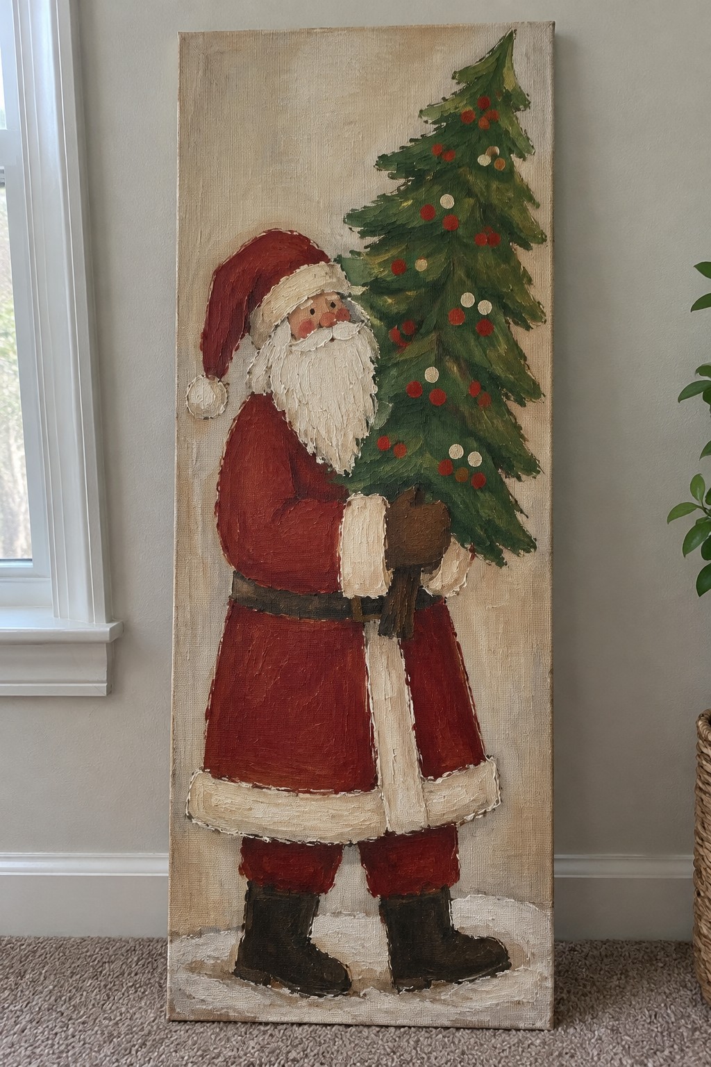Santa in red suit holds ornamented green Christmas tree on textured canvas