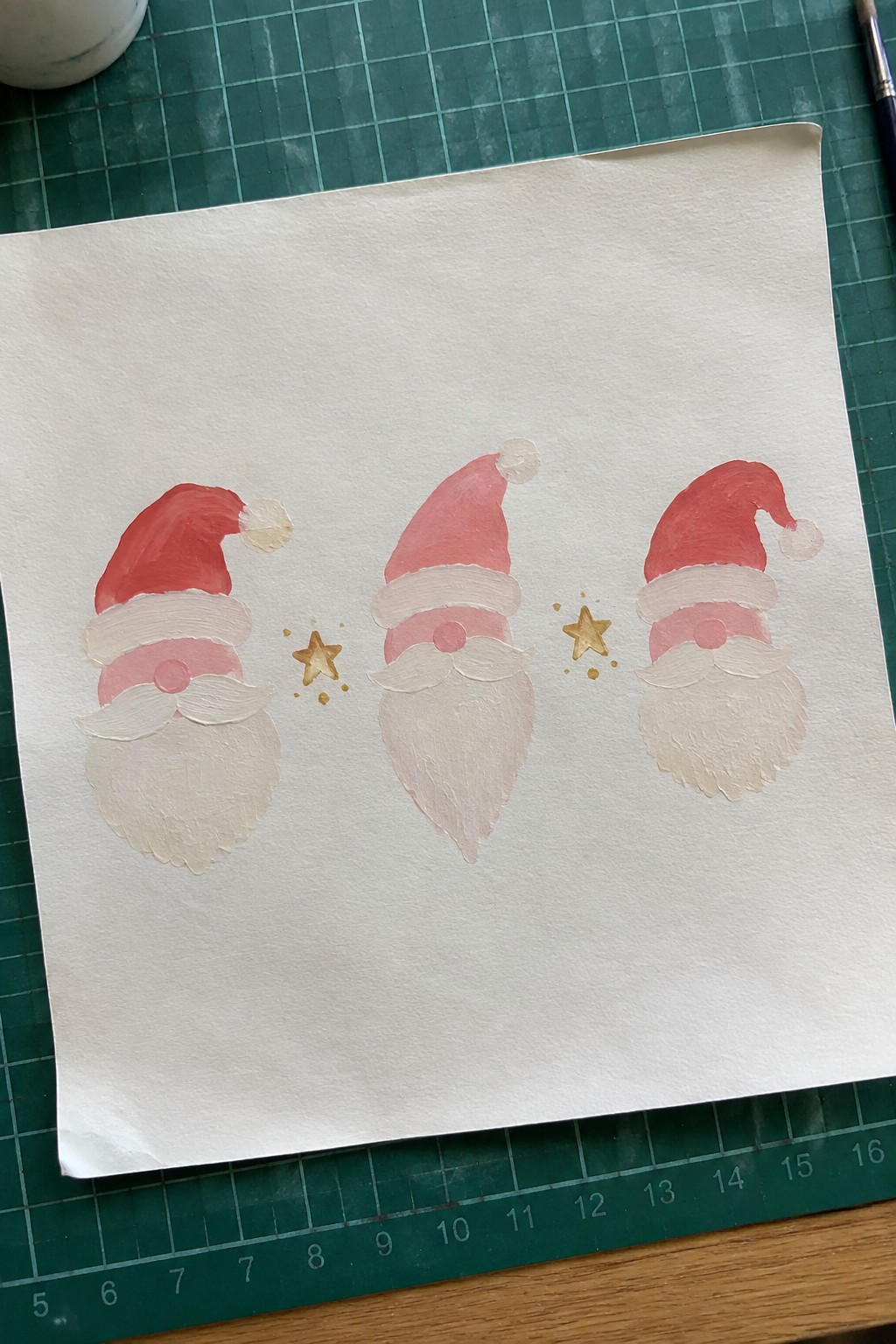 Three hand-painted Santa gnomes with red hats, pink beards, and gold stars