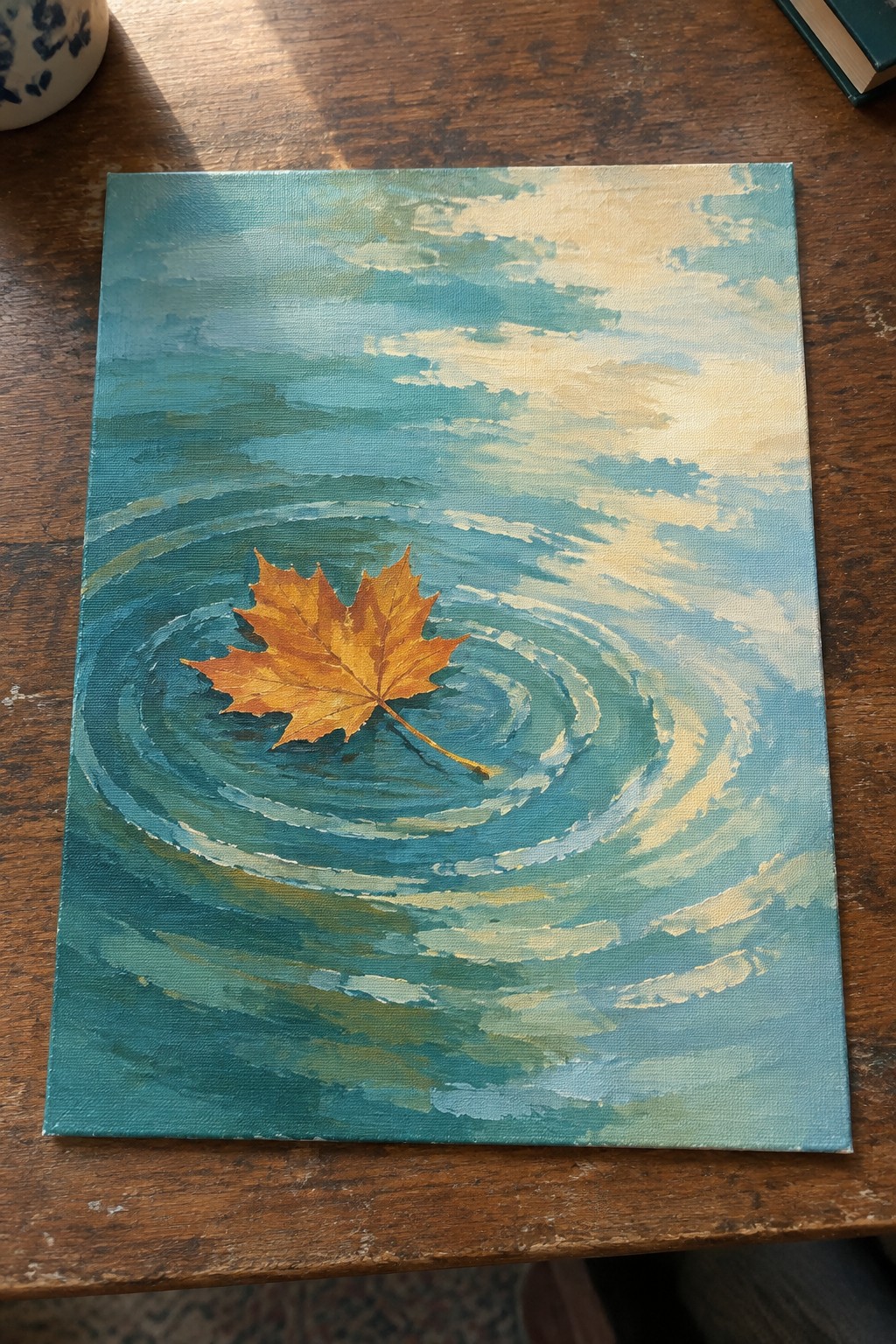 Orange maple leaf floating on rippled blue-green water under a cloudy sky