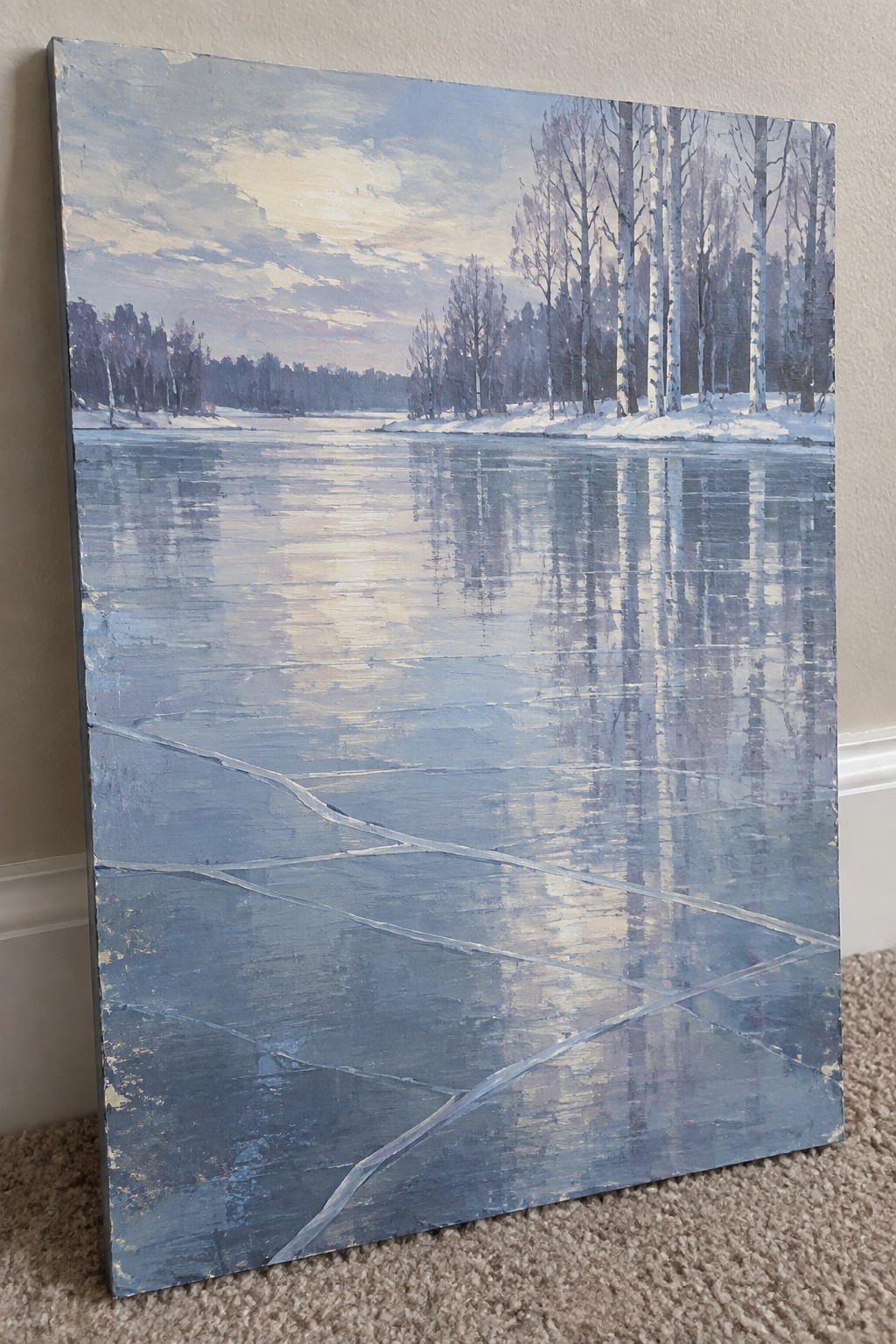 Cracked blue ice on frozen lake reflecting bare birch trees under pale winter sky