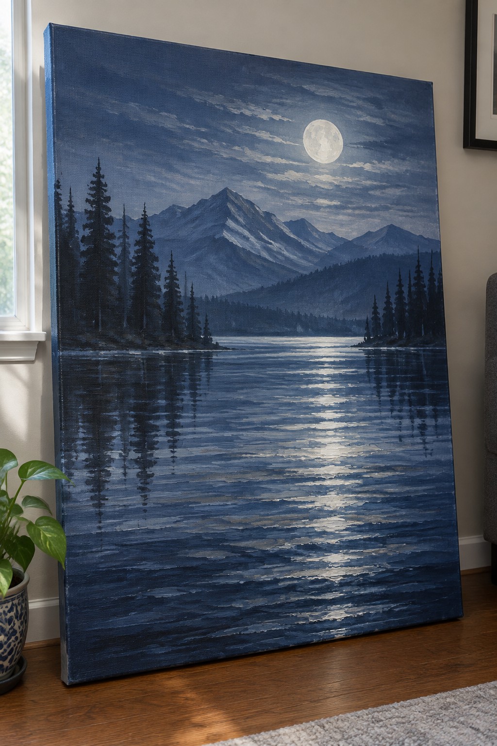 Large landscape painting of moonlit lake and mountains leaning on wall beside plant
