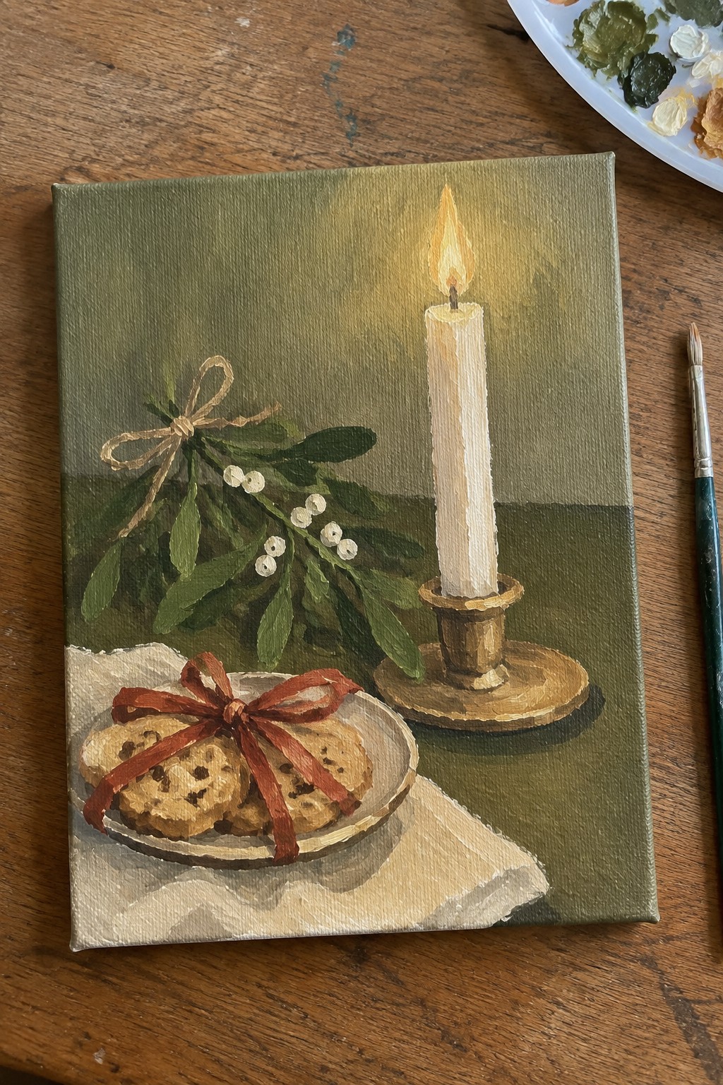 Oil painting of lit candle beside cookies with red ribbon and mistletoe