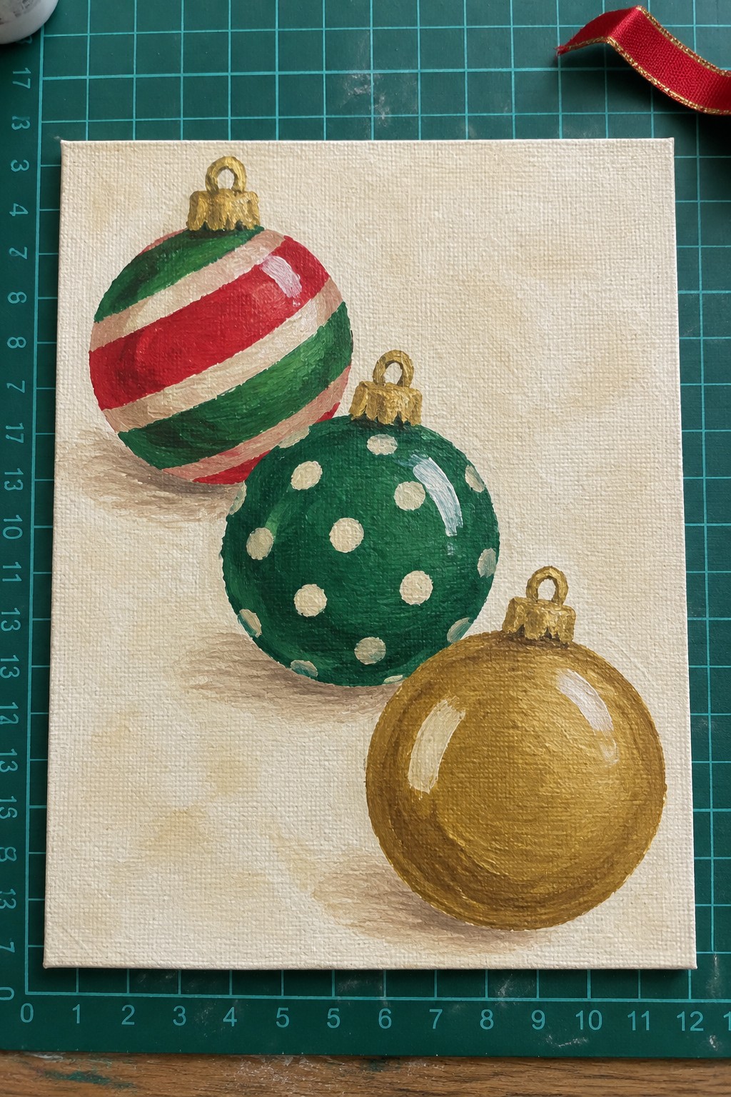 Three Christmas baubles painted on canvas: red-striped, green polka-dotted, and metallic gold.