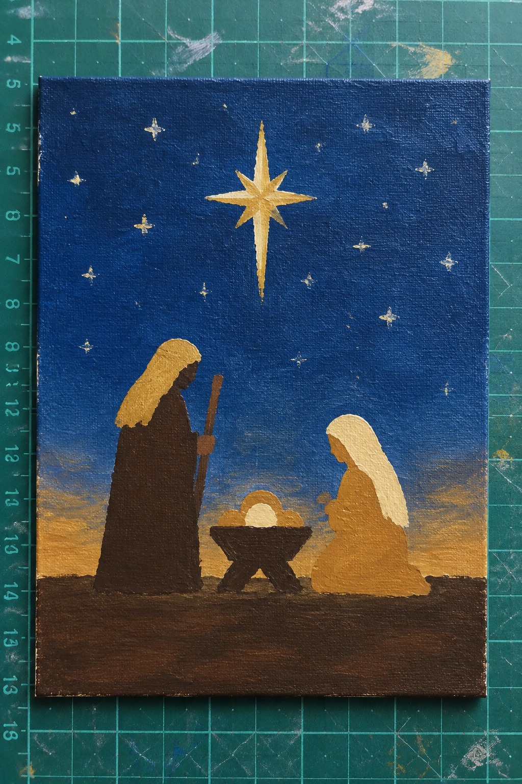 Joseph with staff stands beside kneeling Mary at manger under golden star in starry sky