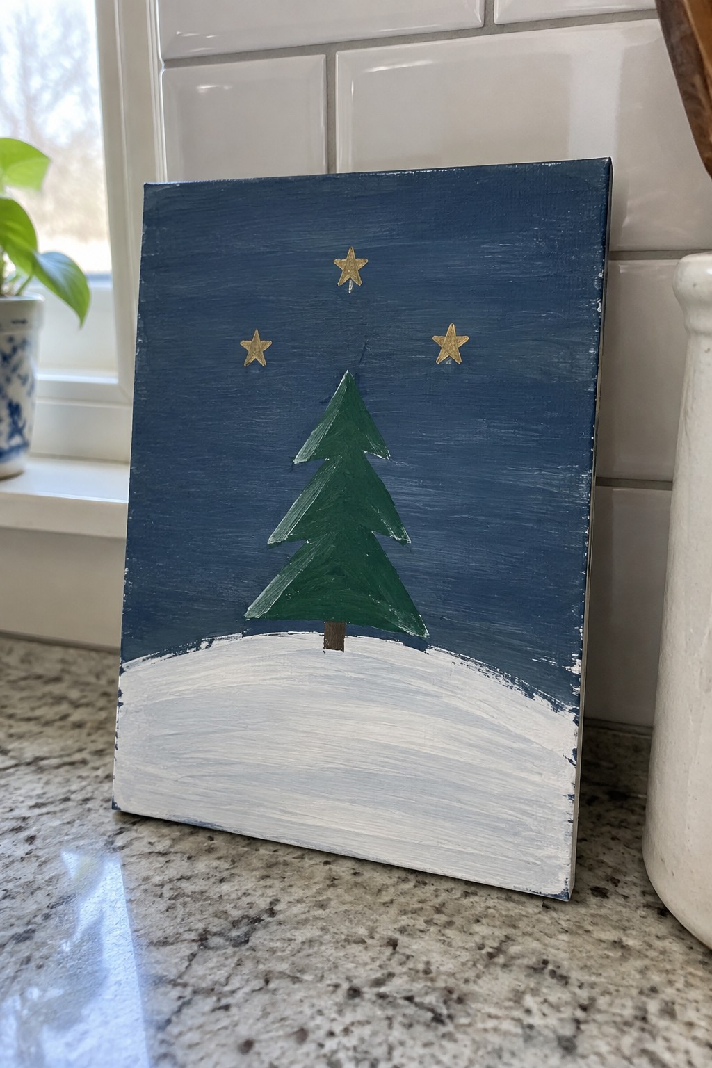Canvas art of green Christmas tree with three gold stars above white snow on blue sky