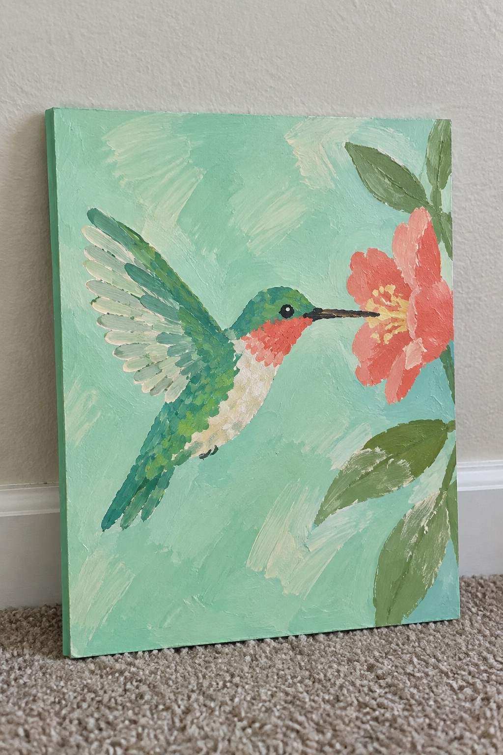 Vibrant painting of green hummingbird hovering near pink flower on teal canvas.