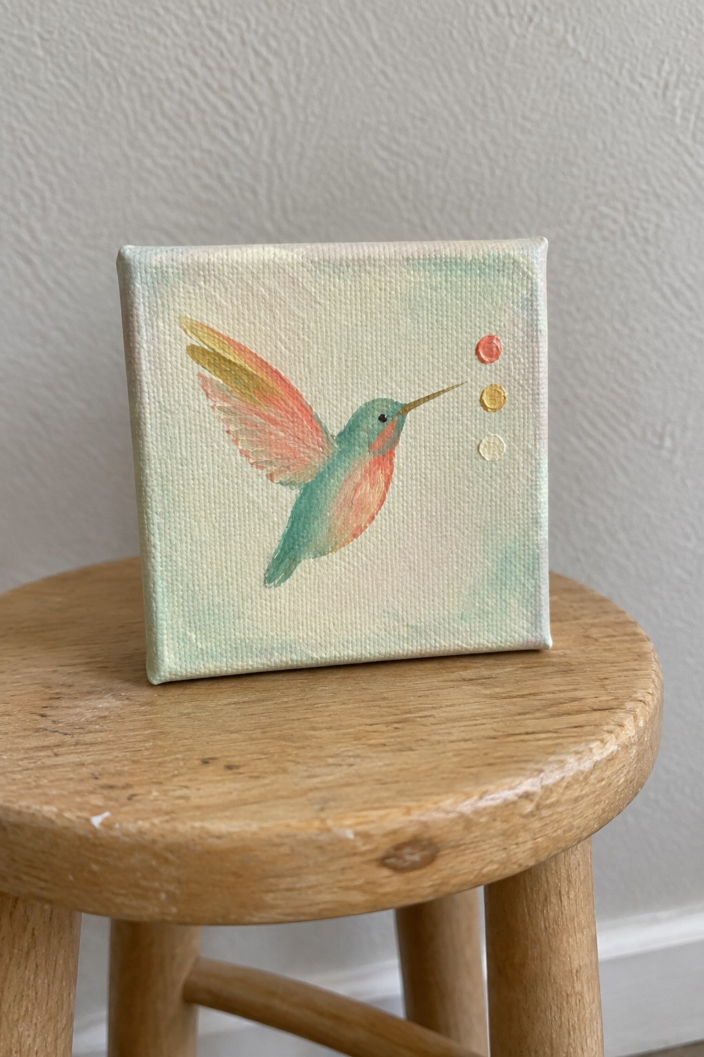 Small canvas painting of colorful hummingbird on wooden stool