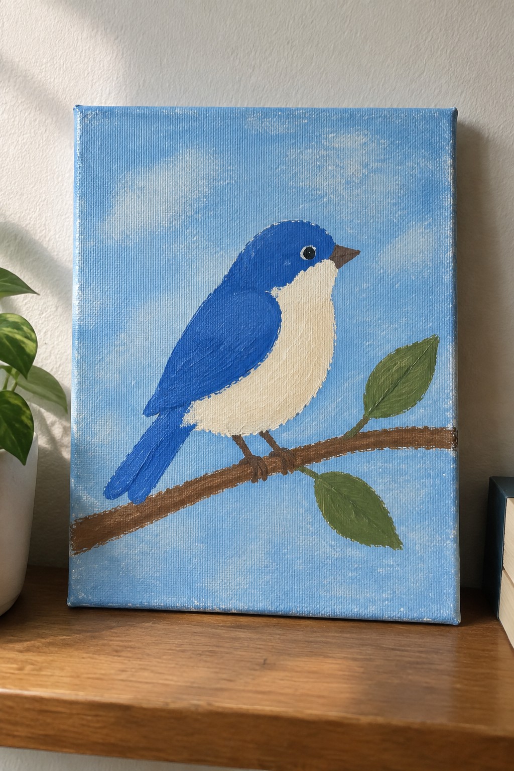 Blue and white bird perched on leafy branch against blue sky on canvas