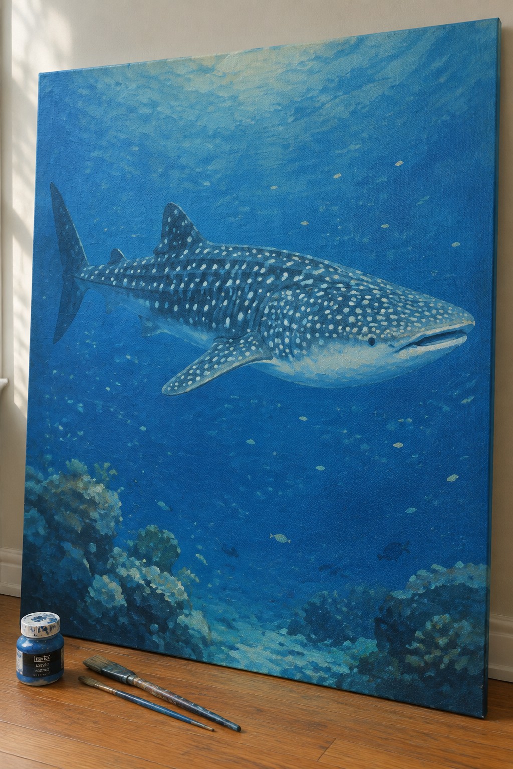 Large whale shark painting on canvas with paint jar and brushes on floor