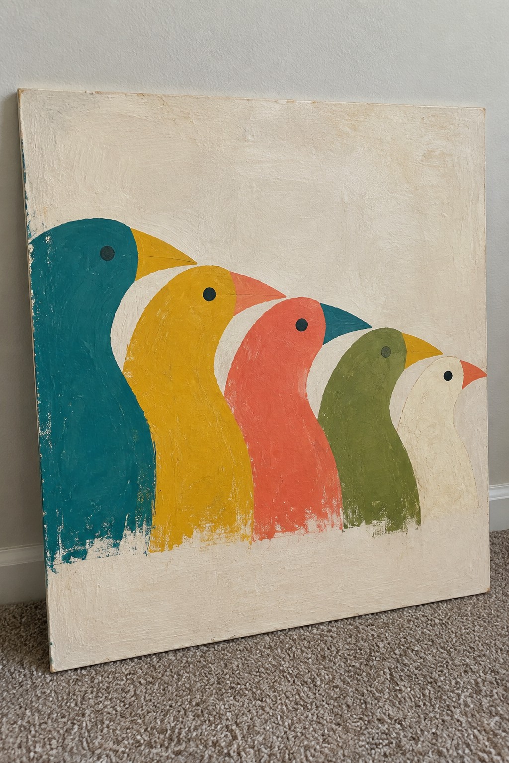 Five colorful stylized birds in a row on textured canvas leaning on wall.